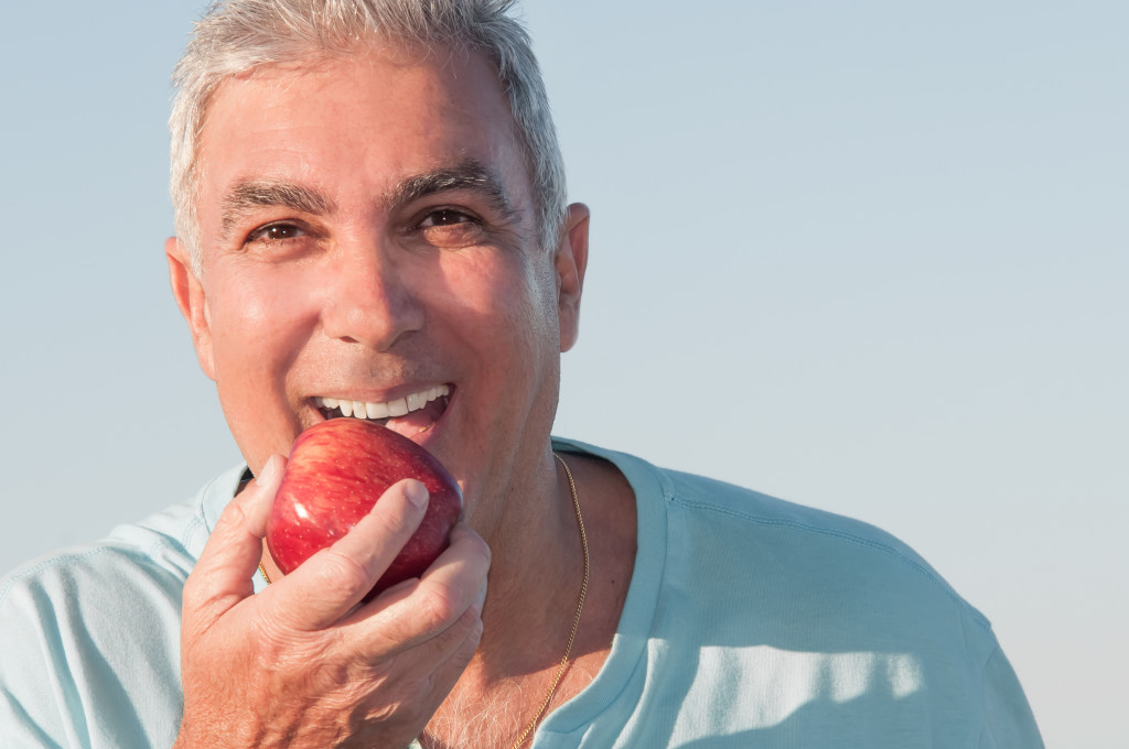 healthy old man eating apple