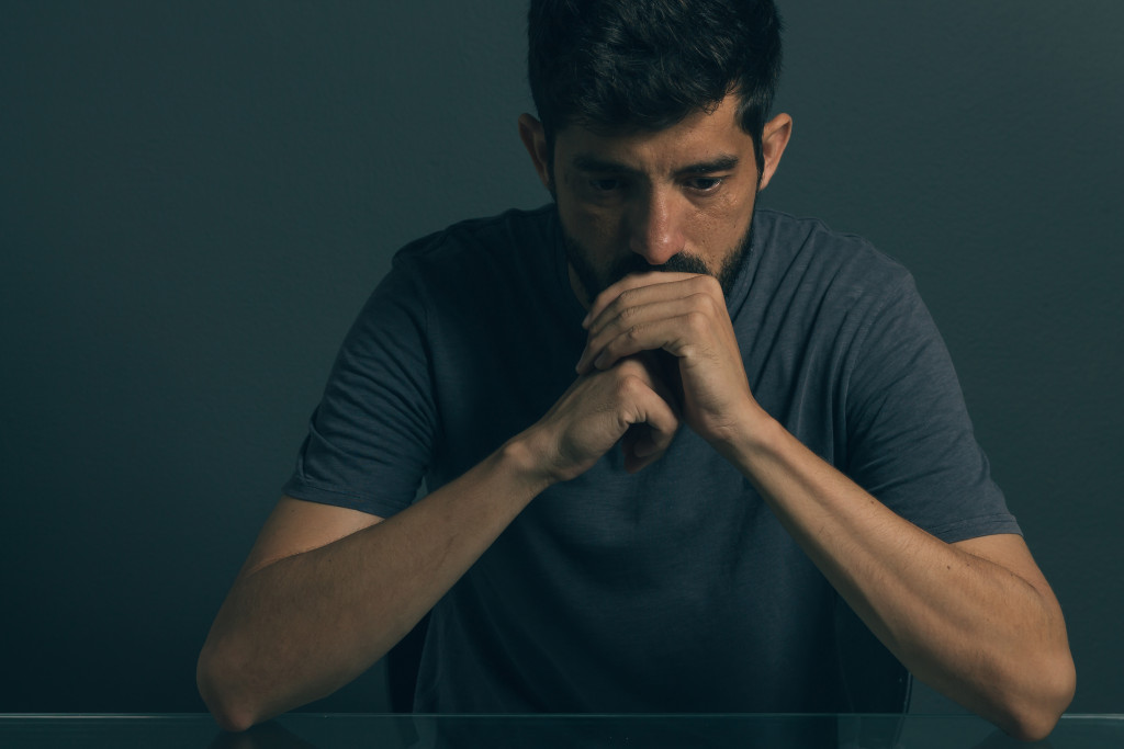 depressed man looking down while holding his fists close together