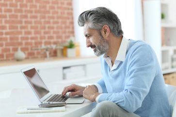 Trendy mature man working from home with laptop