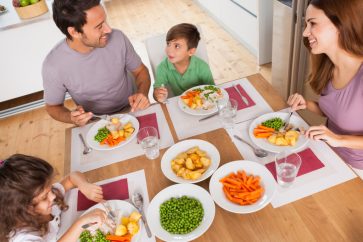 Family smiling around a healthy meal in kitchen