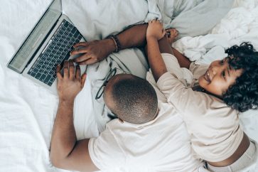 Ethnic child and man with laptop on bed at home