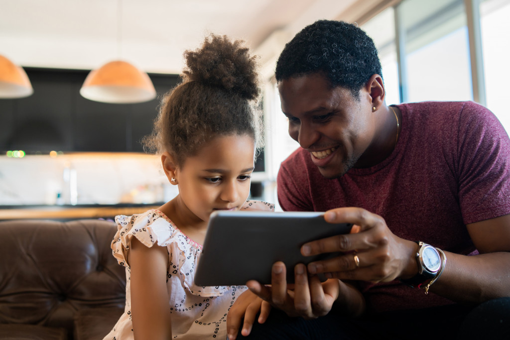 A father and daughter using a tablet at home