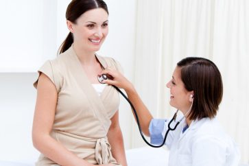 doctor examining female patient with stethoscope