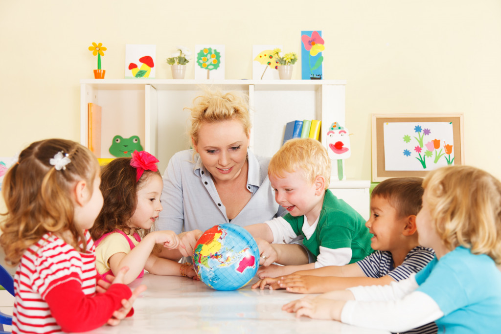 a female teacher engaging children using a globe