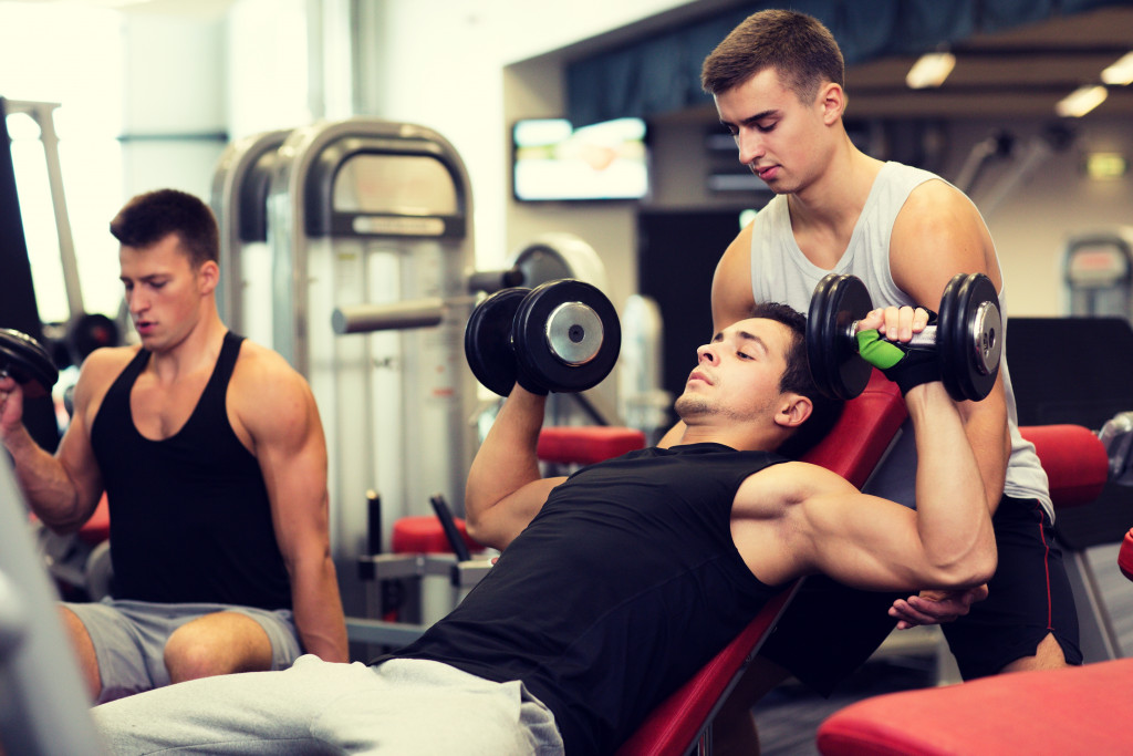 A man working out in a gym with a personal gym trainer