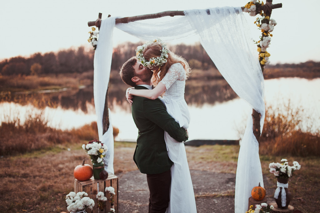 A couple kissing by the lake during their wedding