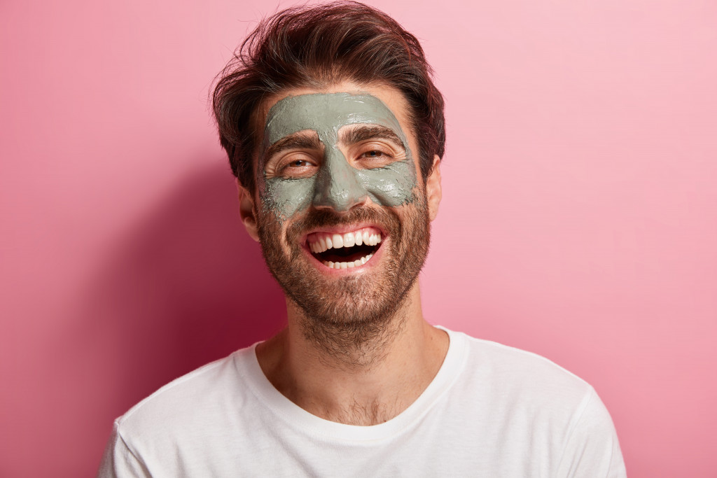A happy man wearing a clay mask