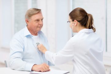 A senior man being check by a female doctor