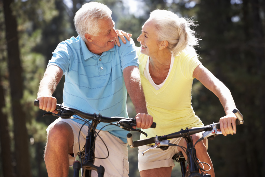 Senior couple riding on bikes in a park.
