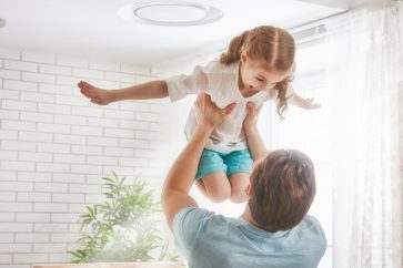 a man holding a little girl high being playful together