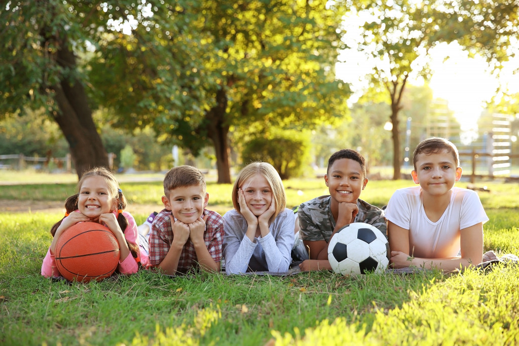 happy children in open park holding basketball and soccerball