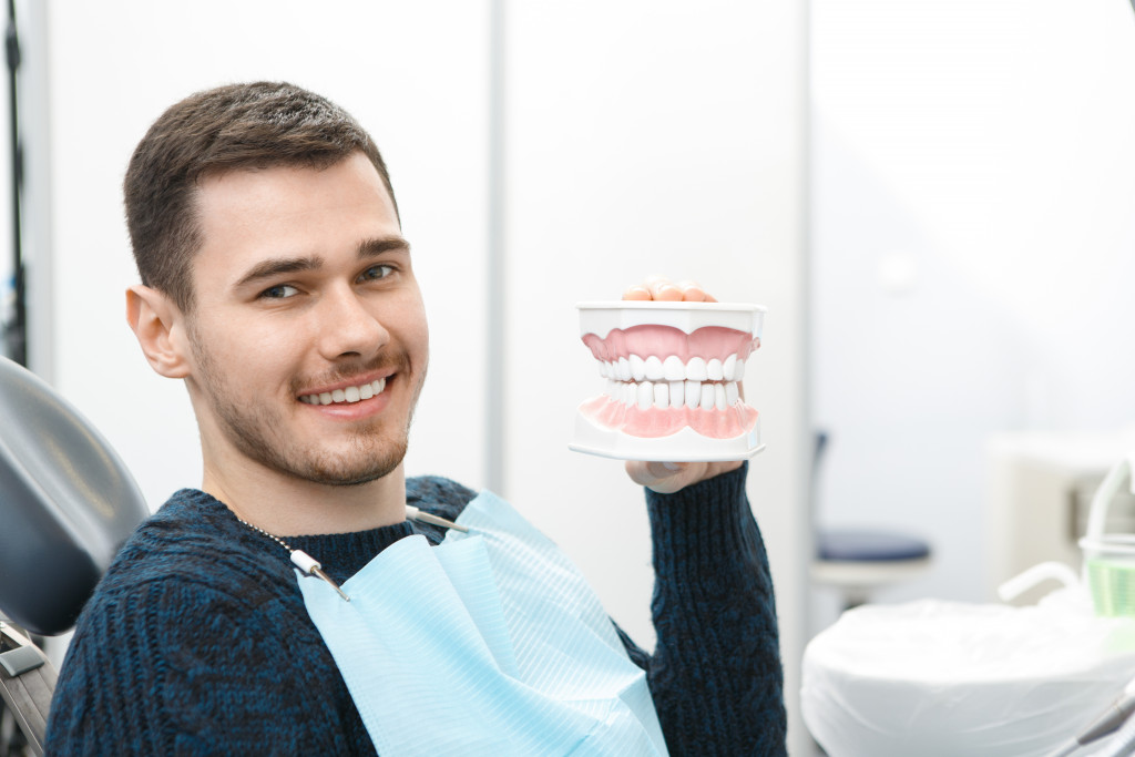 modern dad holding model teeth for dental implants at the clinic