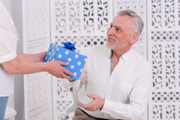 wife giving birthday gift to her senior husband